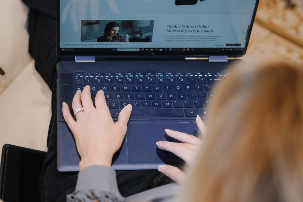 Woman using laptop, marketing website on screen.