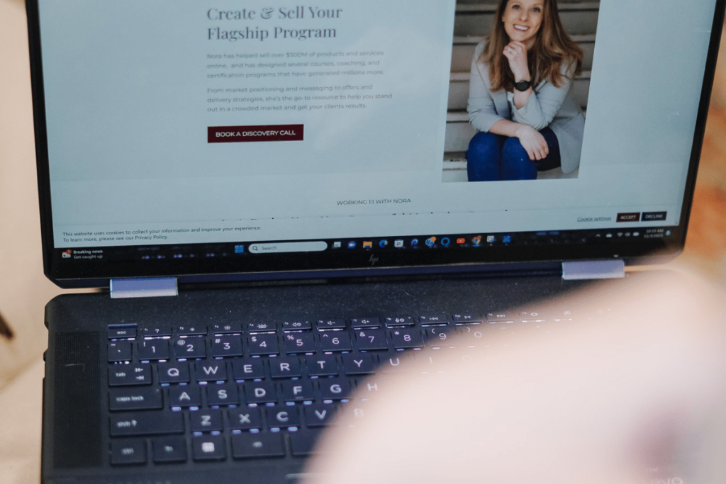 Laptop screen displaying a business coaching webpage with a smiling female expert.