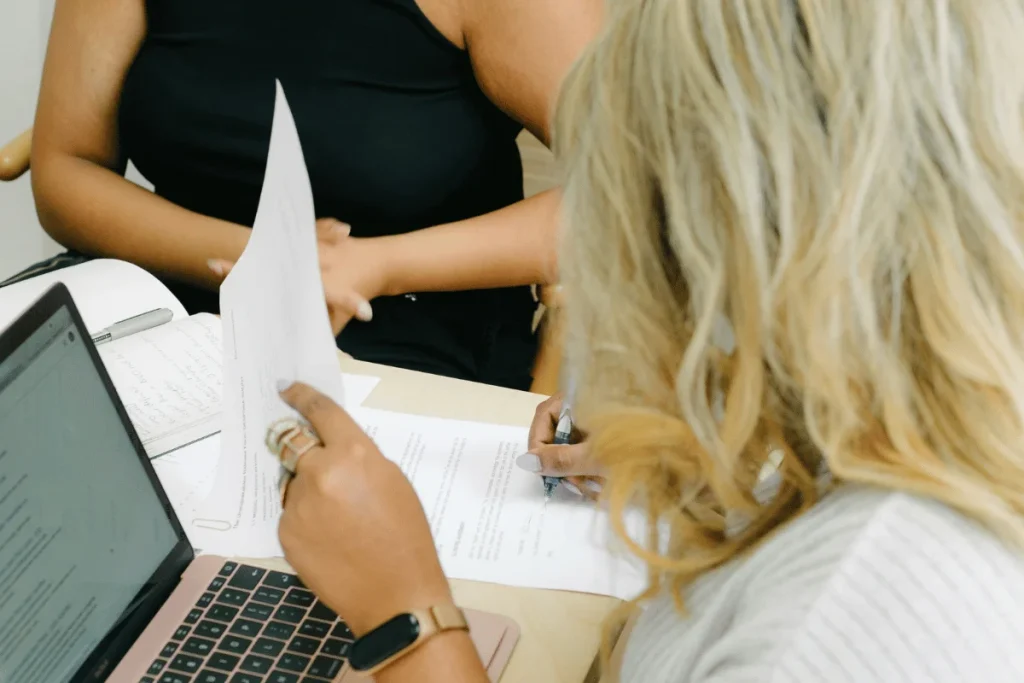 Businesswoman signing papers at a desk.