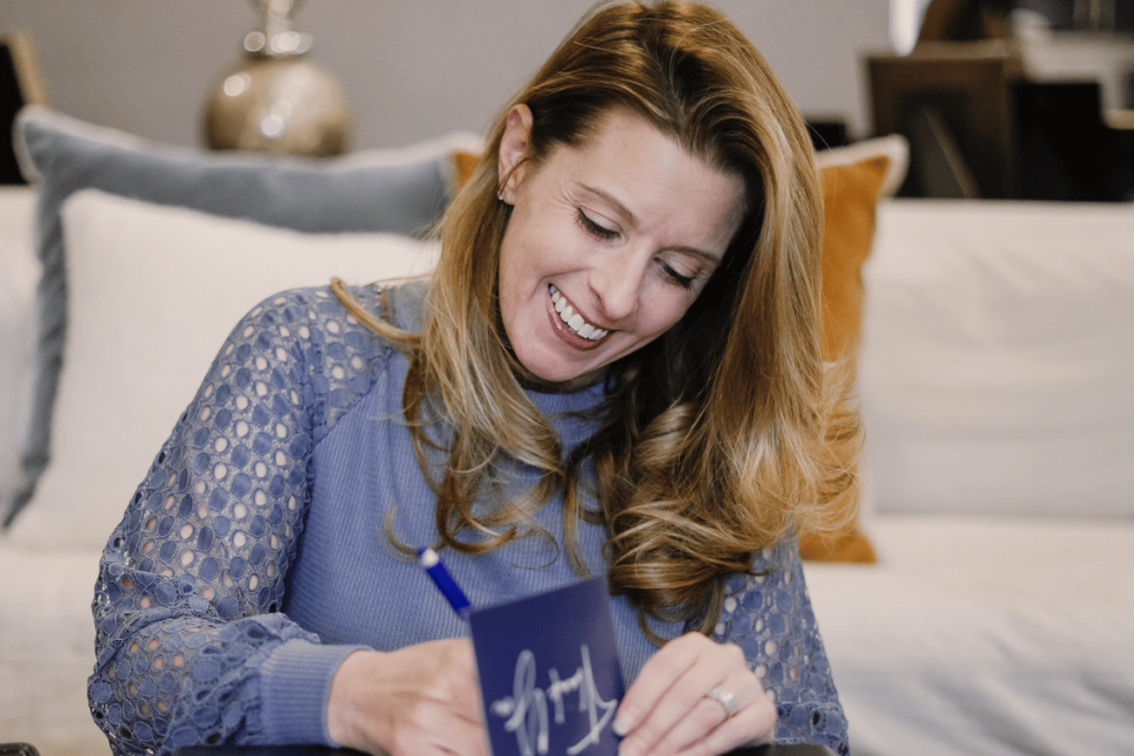 Happy lady in a blue lace top journaling in a bright living room.