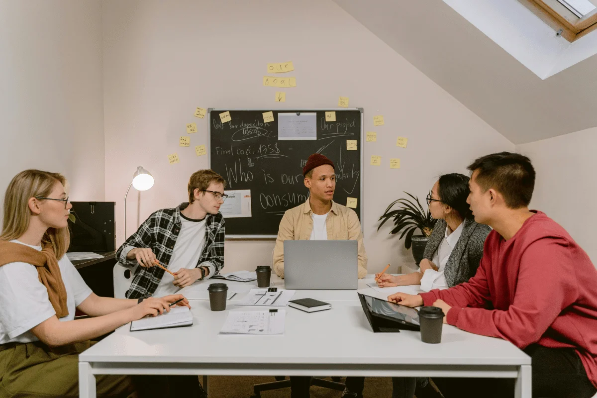 Office team having a discussion, with a blackboard and sticky notes in the background.