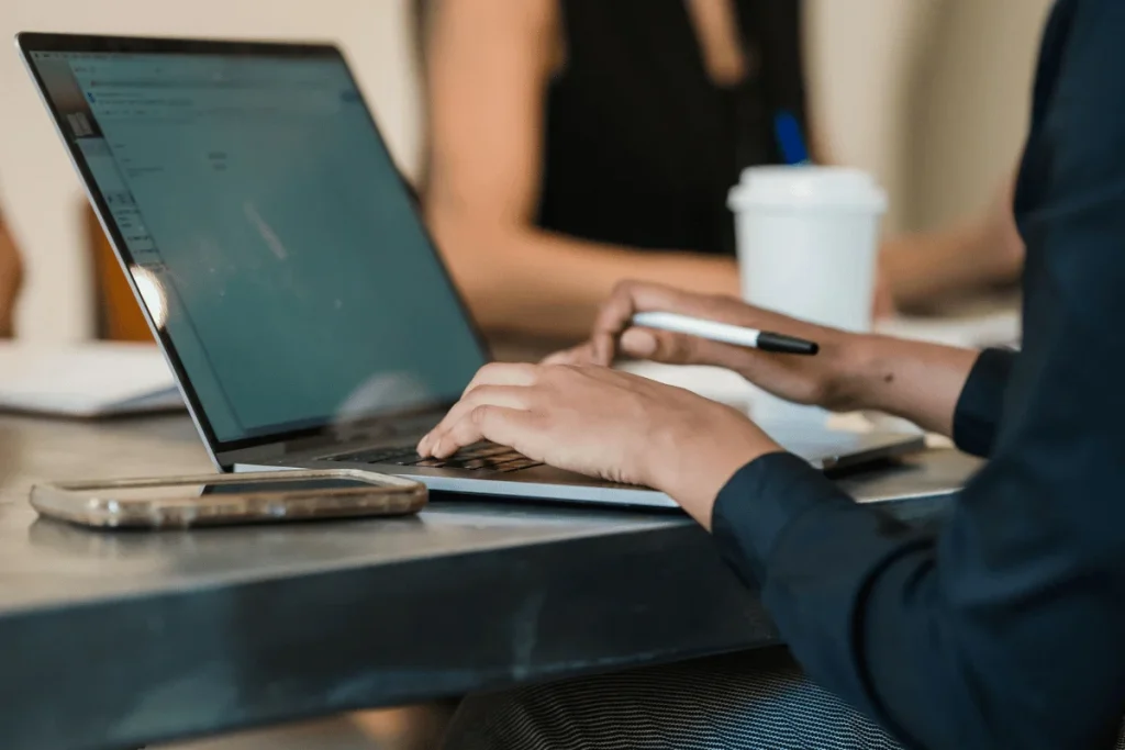 Businessperson working at computer with pen in hand.