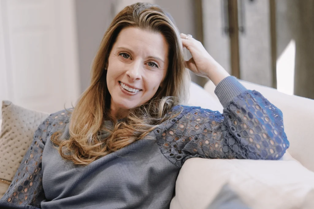 Confident woman with hand in hair sitting on a couch.