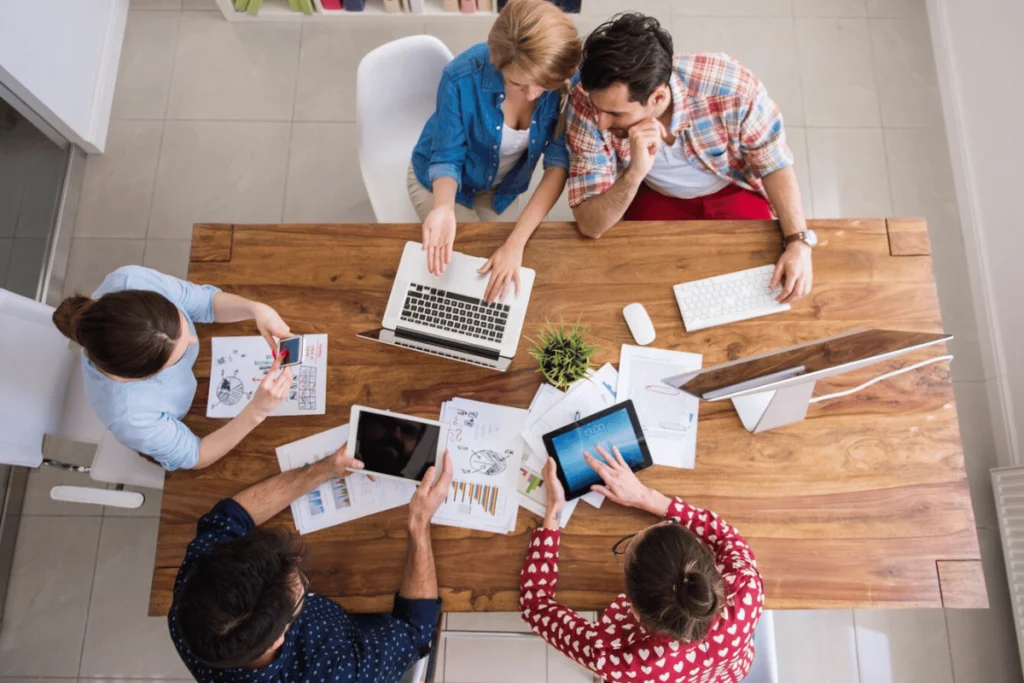 Aerial view of a team collaborating on a laptop, discussing ideas and working together.