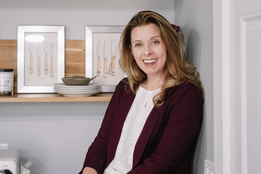 Nora posing indoors with a friendly smile and soft lighting in the background.