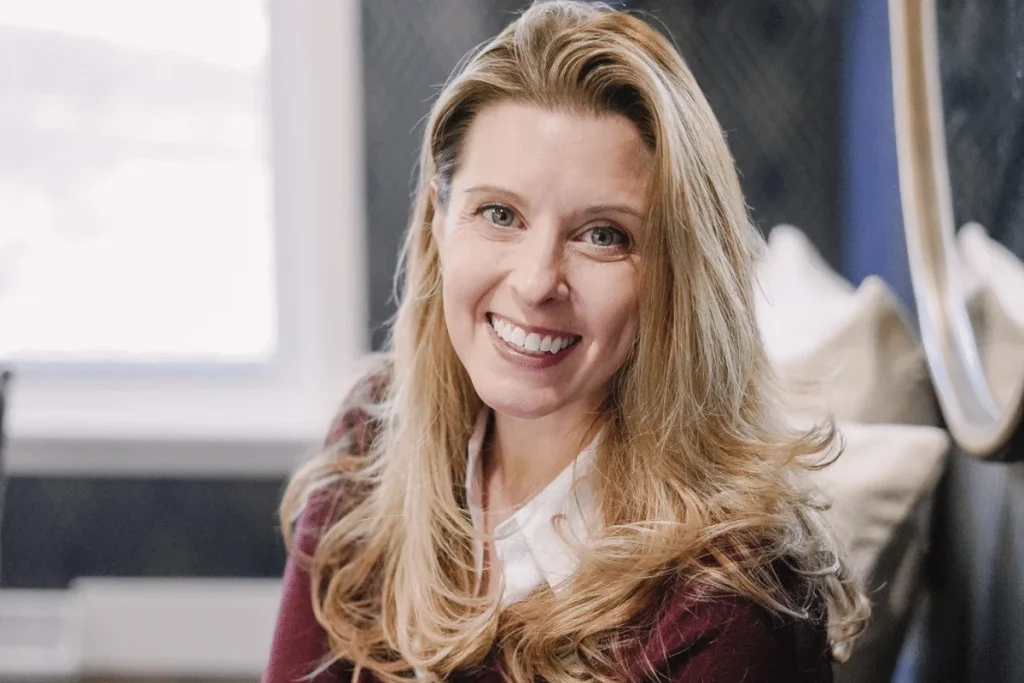 Nora Sudduth with a bright smile, in a room with natural light.