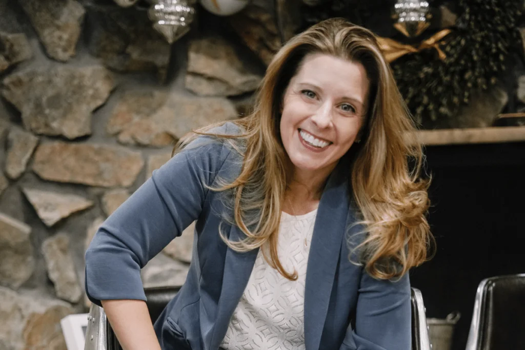 Nora Sudduth smiling in a blue blazer, exuding warmth and professionalism.