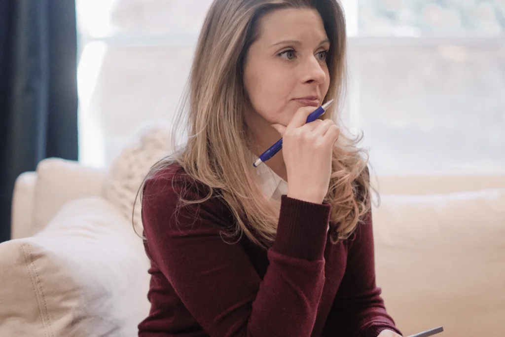 Nora Sudduth with a pen to her lips, deep in thought while writing.