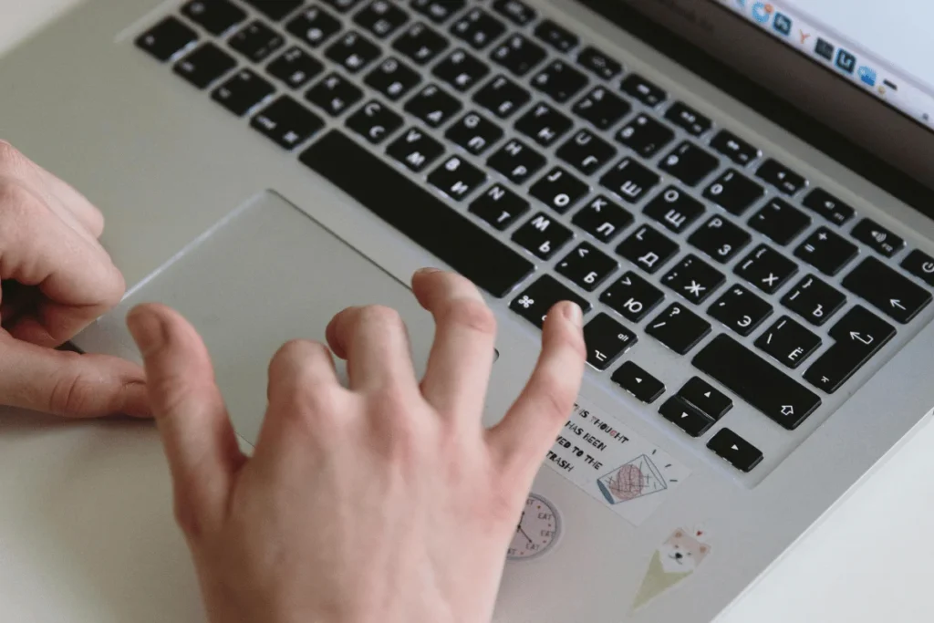Close-up of hands typing on a laptop with cute stickers.