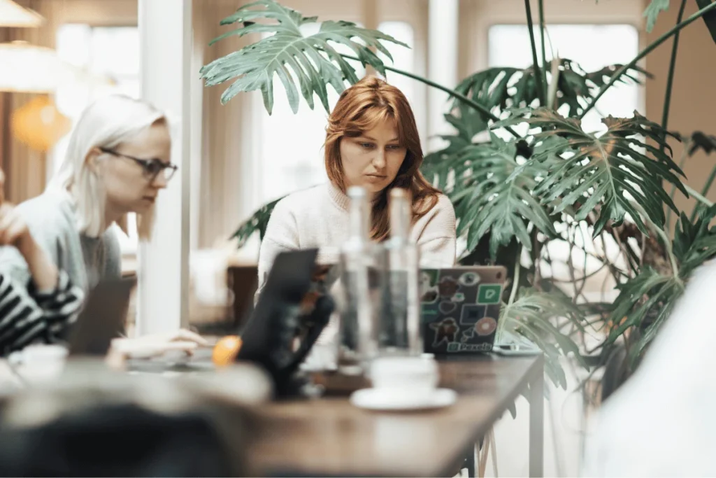Focused woman working on laptop in modern coworking space.