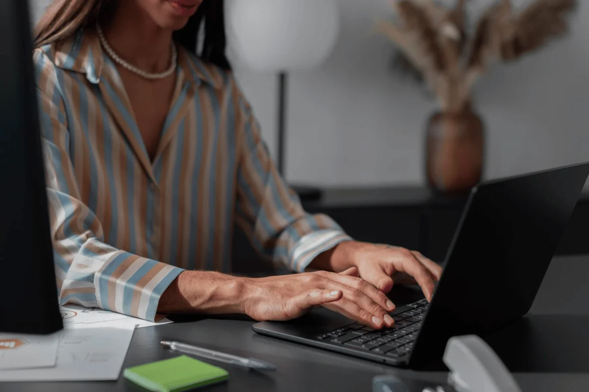 An individual typing on a laptop at a desk.