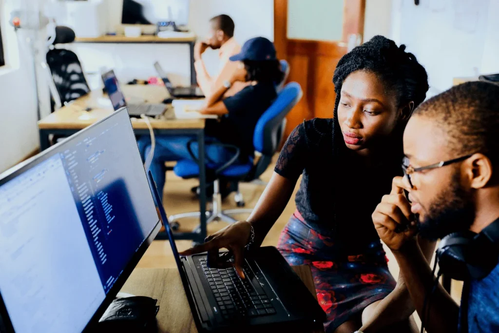 Two coworkers collaborating on a coding project at their workstation.