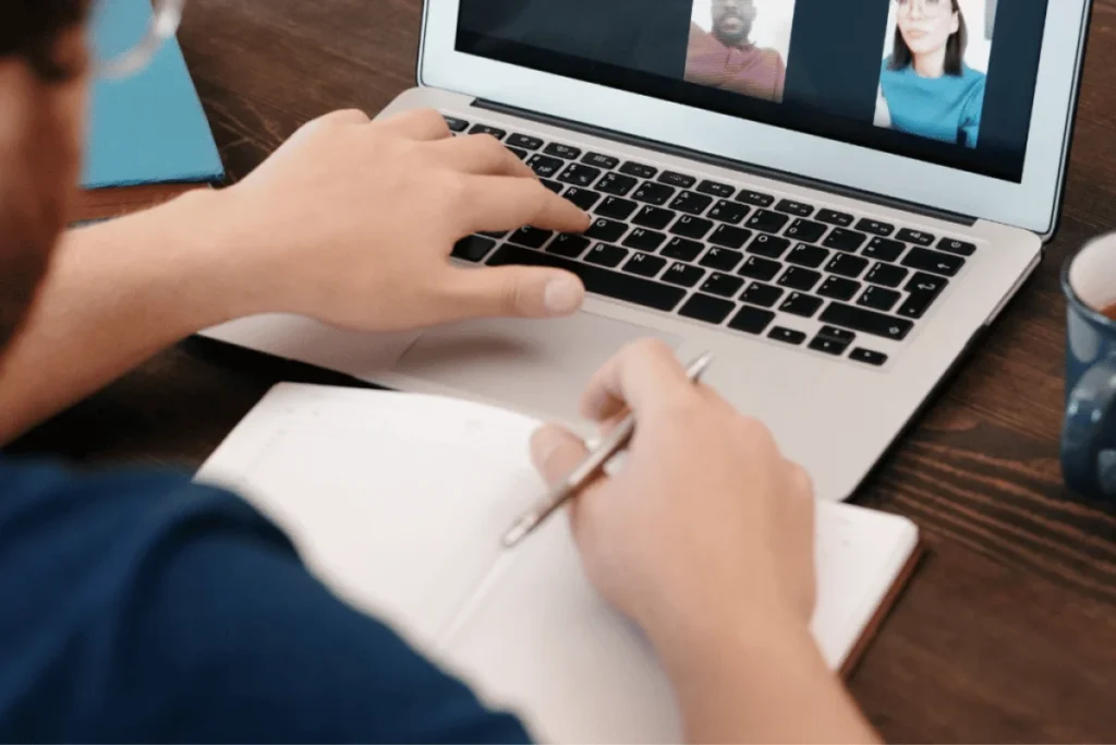 Over-shoulder view of a laptop screen with a video meeting.