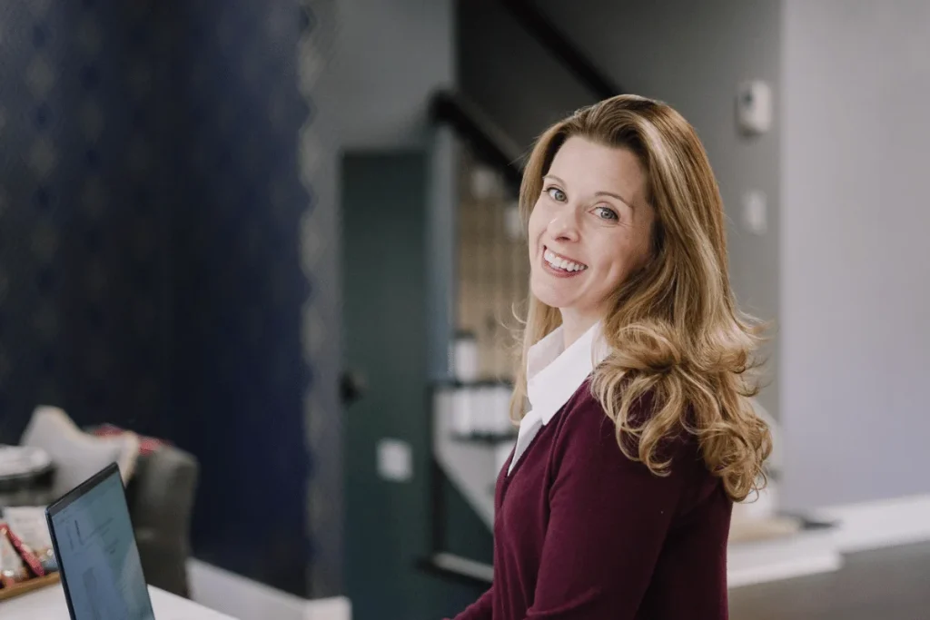 Nora Sudduth smiling over her shoulder with a laptop in the background.