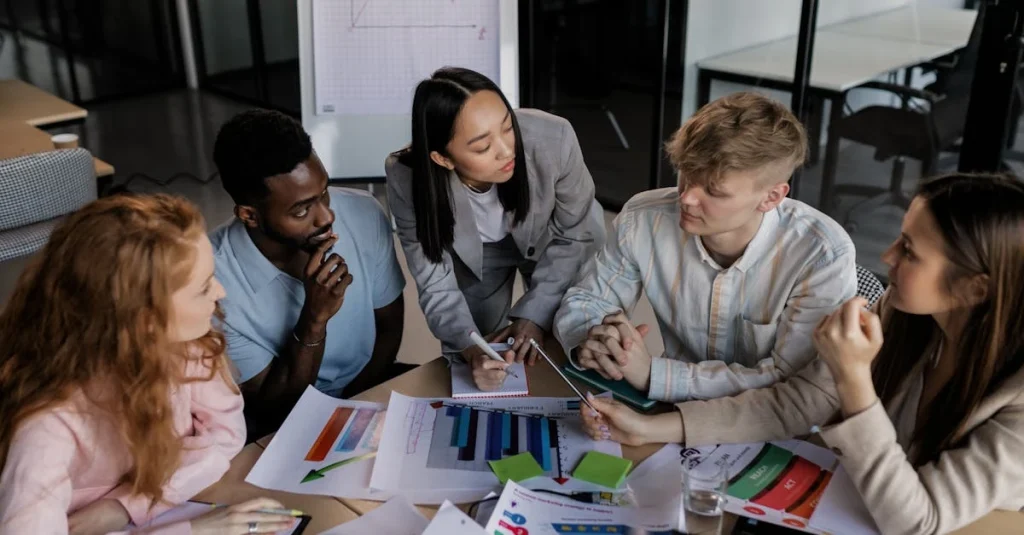 Diverse business team reviewing colorful marketing charts and data to decide to hire marketing consultant for strategy.
