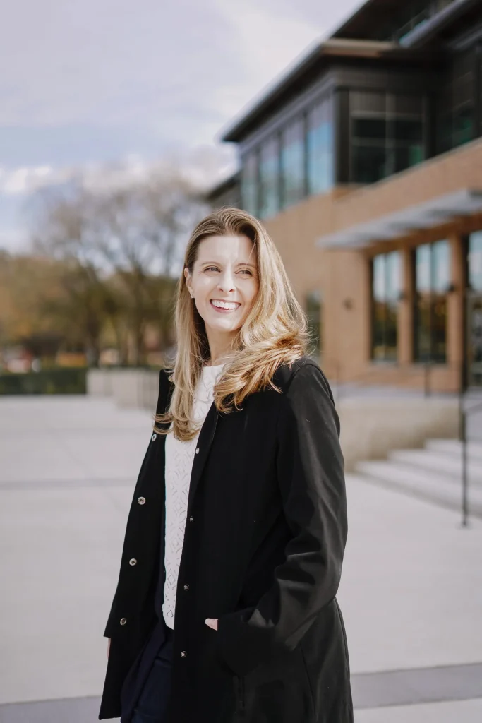 Nora Sudduth standing in front of a modern building on a sunny day.