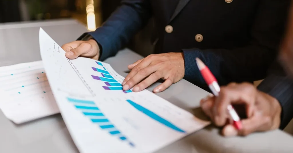 Two professionals reviewing blue bar charts and financial data during customer acquisition due diligence analysis process.