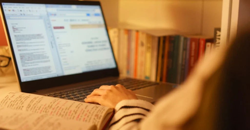 Person at desk with laptop and open book, researching to generate leads with content marketing strategy.