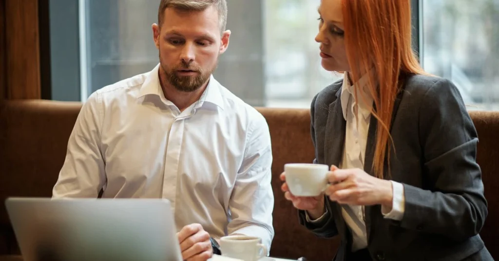 Two professionals discussing content marketing lead generation strategy while reviewing laptop during casual office meeting.