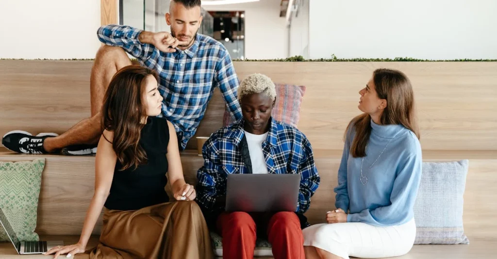 Four diverse professionals collaborating on laptop during customer acquisition consultant team meeting in modern office.